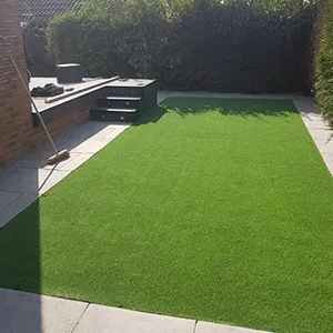a backyard with artificial grass and a grill