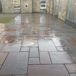a patio with a stone floor and a brick building in the background